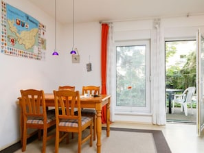 A dining area with a wooden table and chairs, a map on the wall, and a view through a glass door to an outdoor seating area. - Moeller by Interhome (Koserow)
