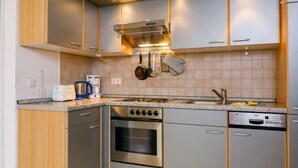 Une cuisine moderne dotée d’appareils électroménagers en acier inoxydable, de meubles en bois et d’un four encastré.