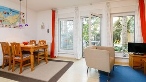Un salon comprenant un coin repas, de grandes fenêtres, un canapé et un téléviseur.