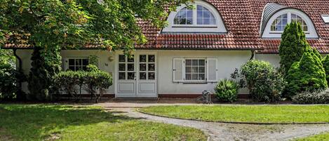 A house with a tiled roof, a white door, and a paved driveway.
