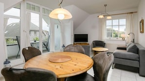A modern living room with a round wooden table, grey sofas, and a TV. - Achterwasser App. 3 by Interhome (Zempin)