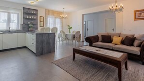 A modern living room with a sofa, coffee table, and dining area with chairs and a table.