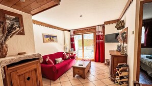 Un salon chaleureux avec un canapé rouge, des meubles en bois et un sol carrelé.