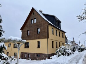 Een meerlaags gebouw met een gevel van bruin hout en een geel gedeelte beneden.