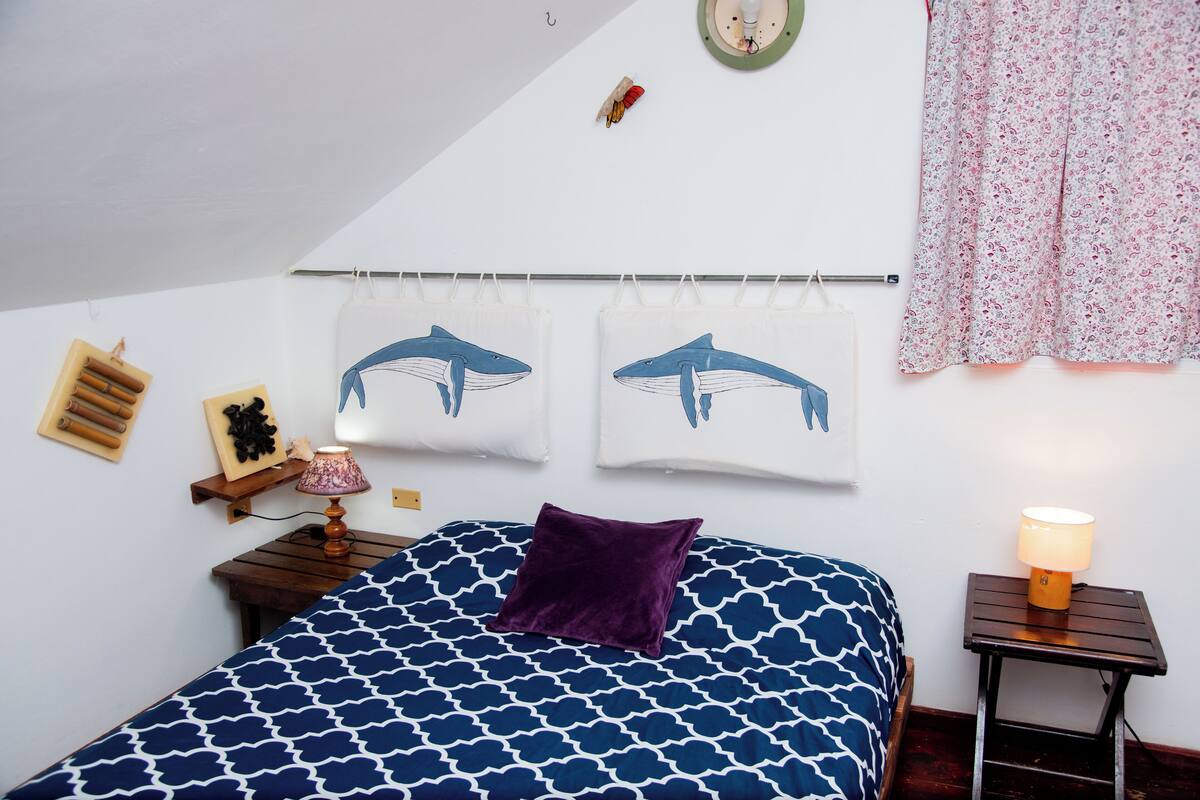 A bedroom with a bed, two wall-mounted curtains, a nightstand, and a lamp.