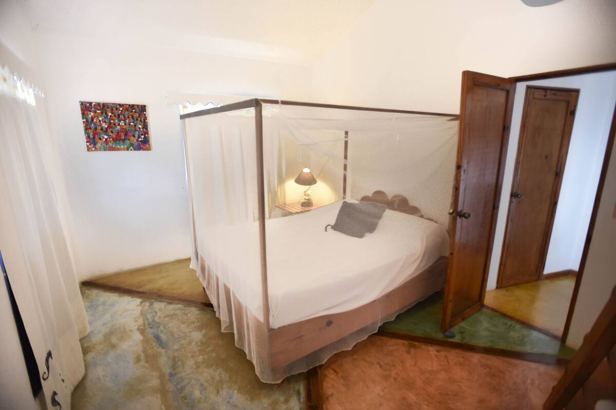 A four-poster bed with a canopy, a bedside lamp, and a small rug on the floor.
