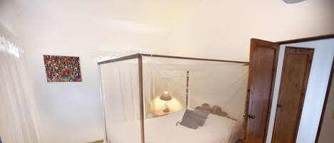 A four-poster bed with a canopy, a bedside lamp, and a small rug on the floor.