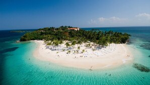Ein Luftbild einer tropischen Insel mit Strand, Palmen und klarem, türkisblauem Wasser.