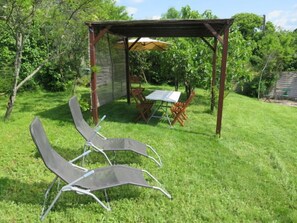 A covered patio area with two lawn chairs and a table, surrounded by a wooden pergola and a fence. - Rillettes by Interhome (Pompadour)