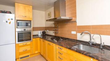 Een koelkast, een magnetron, een oven, kookgerei, borden en bestek