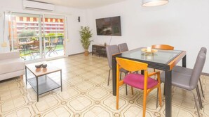 A modern living room with a glass dining table, comfortable seating, a large window, and a potted plant. - Apartment Libra by Interhome (Santa Susanna)