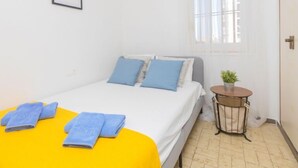 A hotel room with a bed, a small round table with a plant, and a window with curtains. - Apartment Libra by Interhome (Santa Susanna)