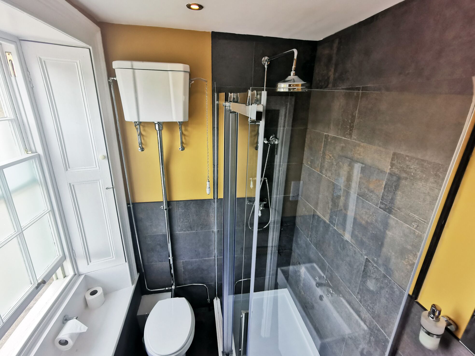 Un baño moderno con inodoro, ducha con mampara de vidrio y lavamanos blanco.