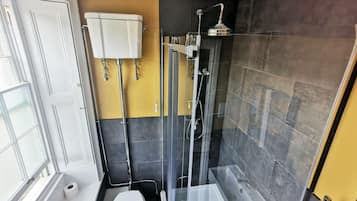 Un baño moderno con inodoro, ducha con mampara de vidrio y lavamanos blanco.