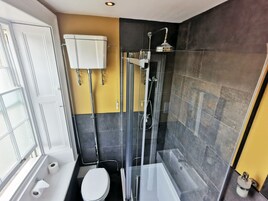 Un baño moderno con inodoro, ducha con mampara de vidrio y lavamanos blanco.