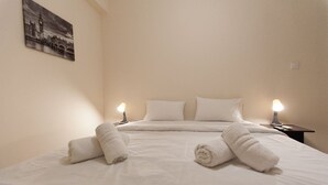 A hotel room with a bed, two bedside tables with lamps, and a painting on the wall. - Acropolis view! (Athina)
