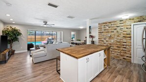 A modern kitchen with a wooden countertop, white cabinets, and a stone backsplash. - The Shiny Diamond in Sarasota. 10 minutes to SIESTA BEACH (Sarasota)