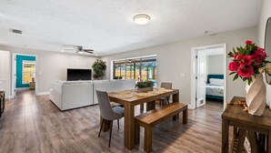 A spacious living room with a wooden dining table, grey sofa, and a ceiling fan. - The Shiny Diamond in Sarasota. 10 minutes to SIESTA BEACH (Sarasota)