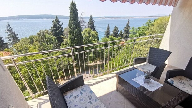 Ein Balkon mit Korbmöbeln und Meerblick.