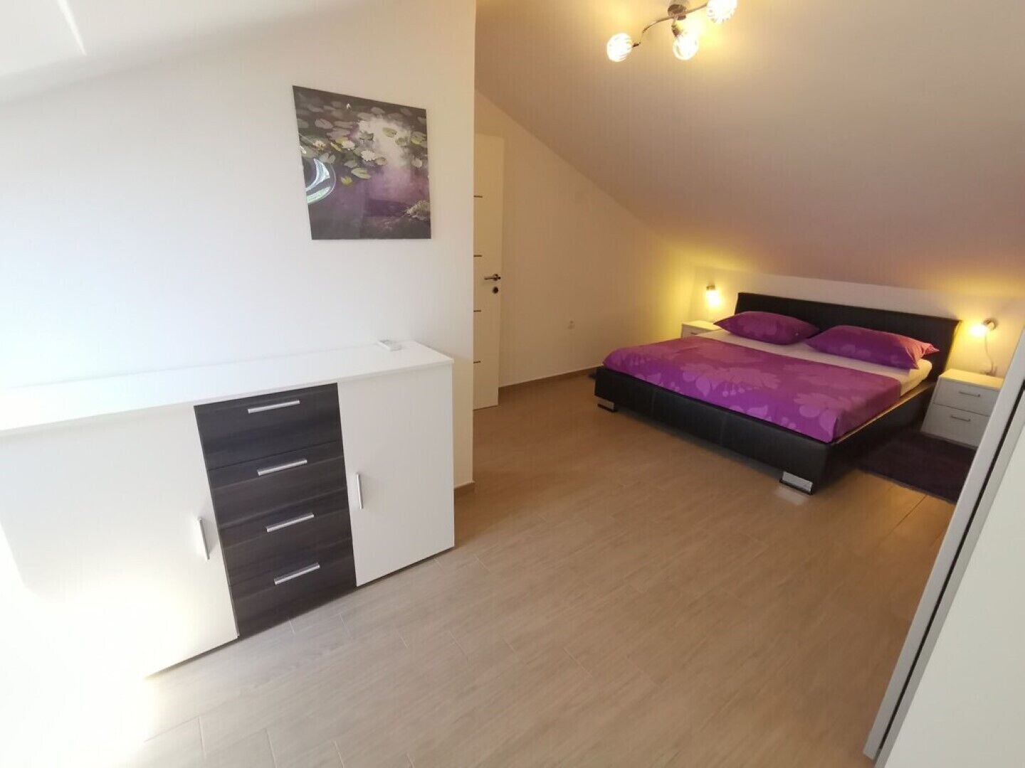 A bedroom with a bed, bedside tables, a wardrobe, and a ceiling light fixture.