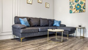 A modern living room with a grey sectional sofa, a round coffee table, and a small side table. - Hot Tub Haven w/ King Bed + More (Greater Sudbury)