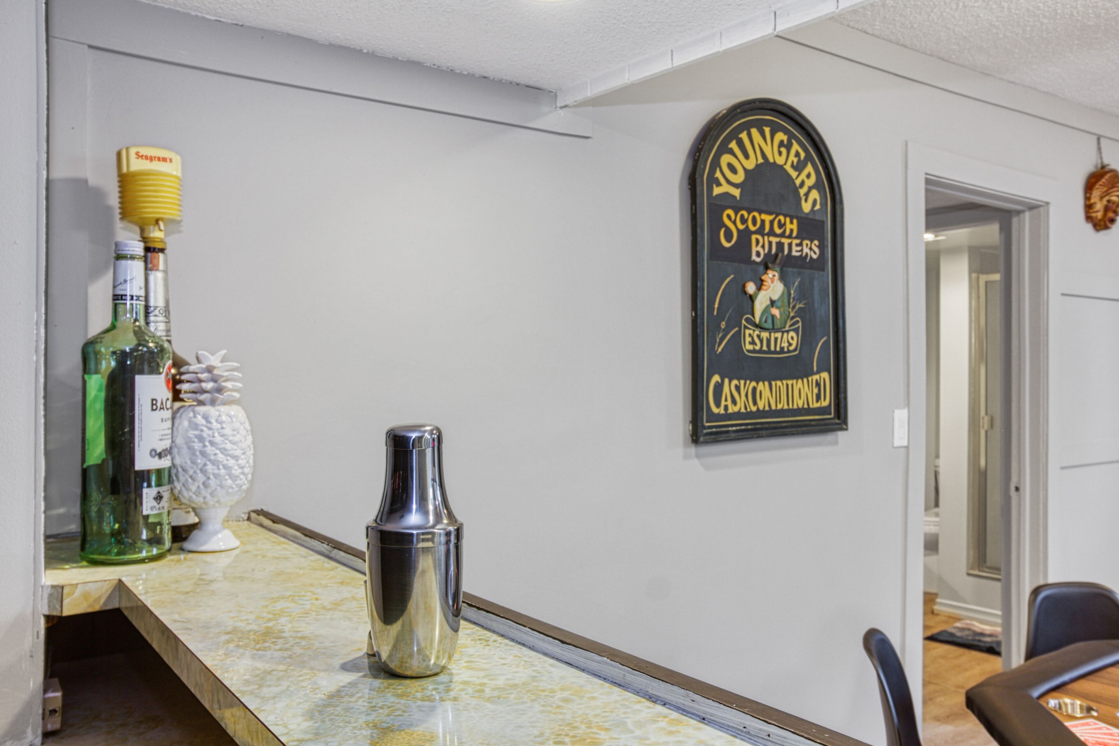 A bar area with a cocktail shaker, bottles, and a sign reading "Younger Scotch Bitters".