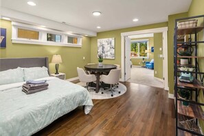 Een slaapkamer met een bed, nachtkastje, lamp en een ronde tafel met stoelen.