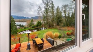 A deck with a table and chairs, overlooking a lake and forest. - Elegant 4400sf Villa w/ Lk. & Mt. view | Sammamish (Sammamish)