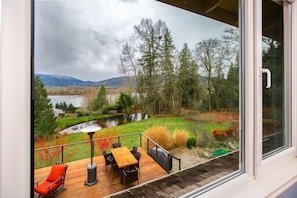 Une terrasse avec une table et des chaises, offrant une vue sur un lac et une forêt.