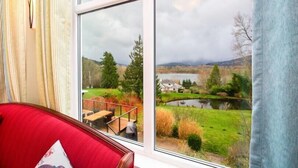 A room with a large window overlooking a scenic landscape with a lake, trees, and a distant house. - Elegant 4400sf Villa w/ Lk. & Mt. view | Sammamish (Sammamish)