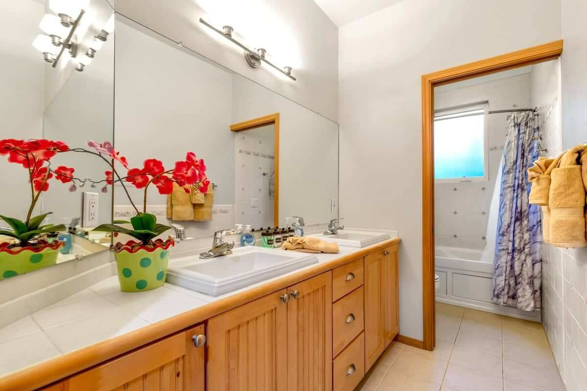 Un baño con dos lavamanos, un espejo grande, armarios de madera y una zona de ducha.