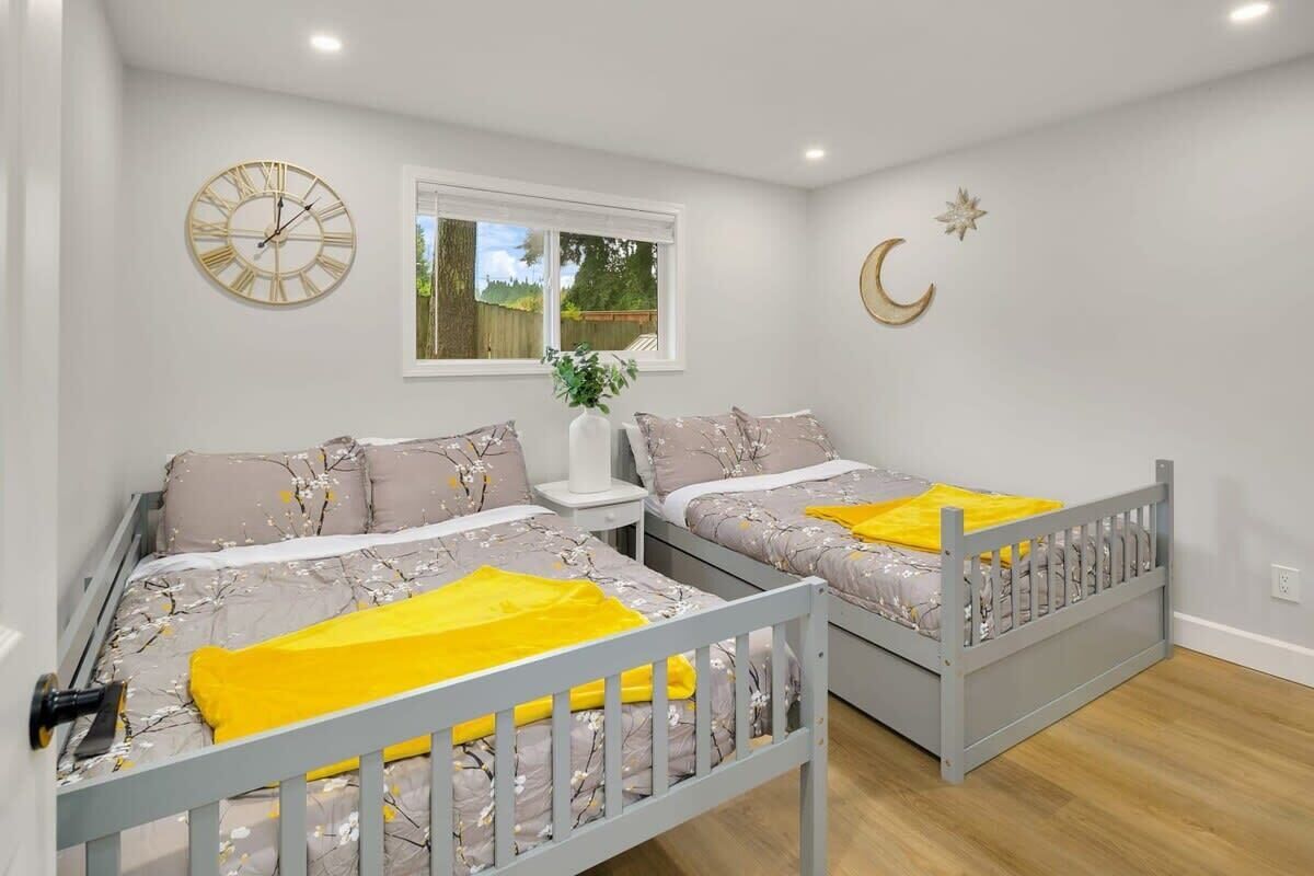 A bedroom with two beds, a wall clock, a window, and a crescent moon decoration.