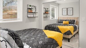 A bedroom with two beds, a large mirror, and shelves with decorative items. - Brand New Designer's Modern, 1BR Home 1min to I-5 (Lynnwood)