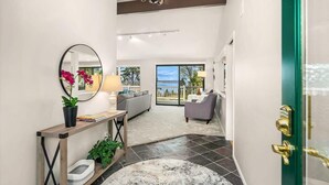 A modern interior with a console table, a round mirror, a sofa, and a view to the outside. - Family Retreat w Lake & Mt & City View, Gym, MI (Mercer Island)