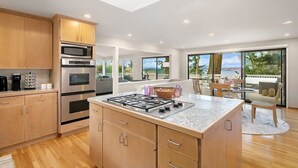 A modern kitchen with wooden cabinets, a gas stove, and built-in ovens. - Family Retreat w Lake & Mt & City View, Gym, MI (Mercer Island)