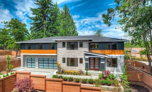 A modern two-story house with a stone facade, large windows, and a garage.