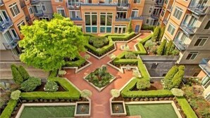 A residential building with a central courtyard featuring geometric landscaping, including hedges and a tree. - DT Designer's 2BR Condo Parking, Tub, Pool - 99 walk score (Seattle)