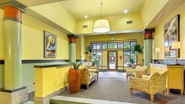 A lobby with a reception desk, seating area, and a staircase leading to upper floors. - DT Designer's 2BR Condo Parking, Tub, Pool - 99 walk score (Seattle)