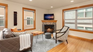 A living room with a fireplace, a TV, a sofa, and a patterned armchair.