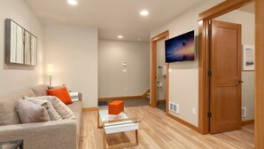 A modern living room with a sofa, a coffee table, a TV, and a wooden door.