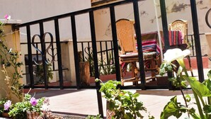A balcony with a metal railing, wicker chairs, and a striped umbrella. -  Solsticio Copacabana (Copacabana)