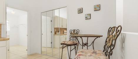 Una habitación con un armario espejado, una pequeña mesa con una silla y dos cuadros colgados en la pared.