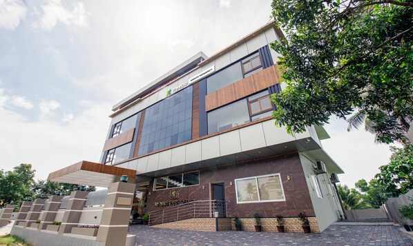A modern building with a 'WAY IN' sign, a 'WAY OUT' sign, and a 'AMIGOS RESIDENCY' sign. - Treebo Amigos Residency Cochin Airport Hotel (Aluva)