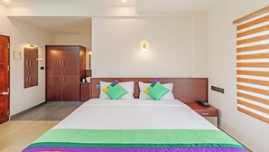 A hotel room with a large bed, a nightstand, a phone, and a wooden wardrobe. - Treebo Amigos Residency Cochin Airport Hotel (Aluva)