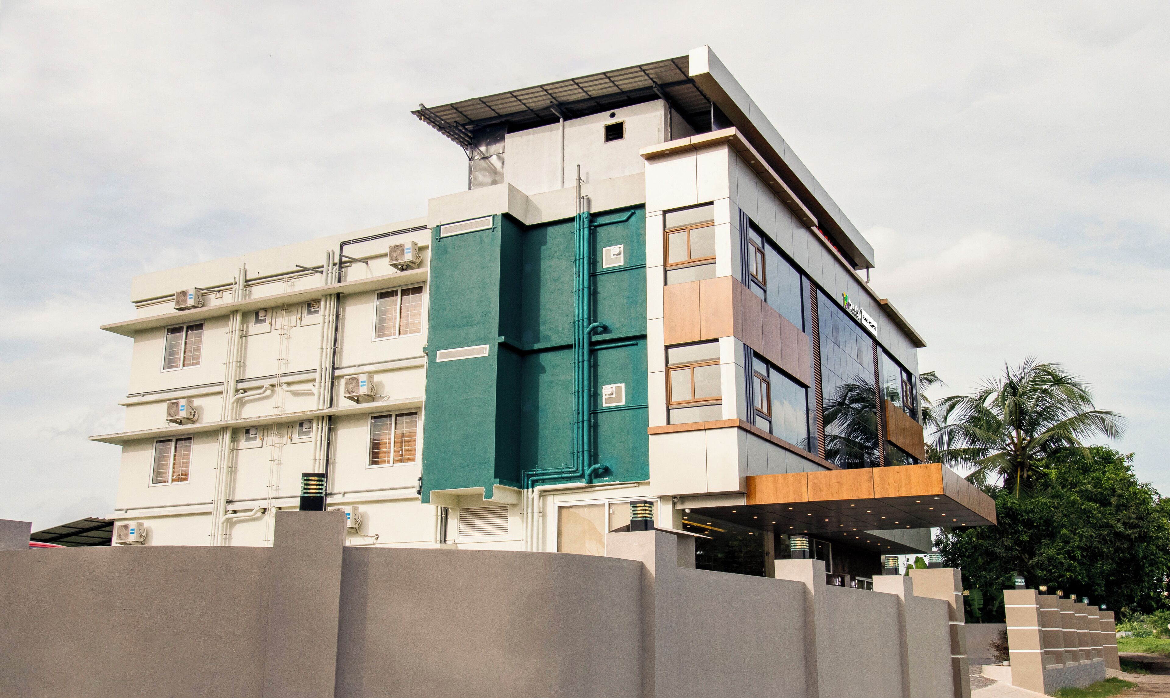 A multi-story building with a flat roof, large windows, and a green door.