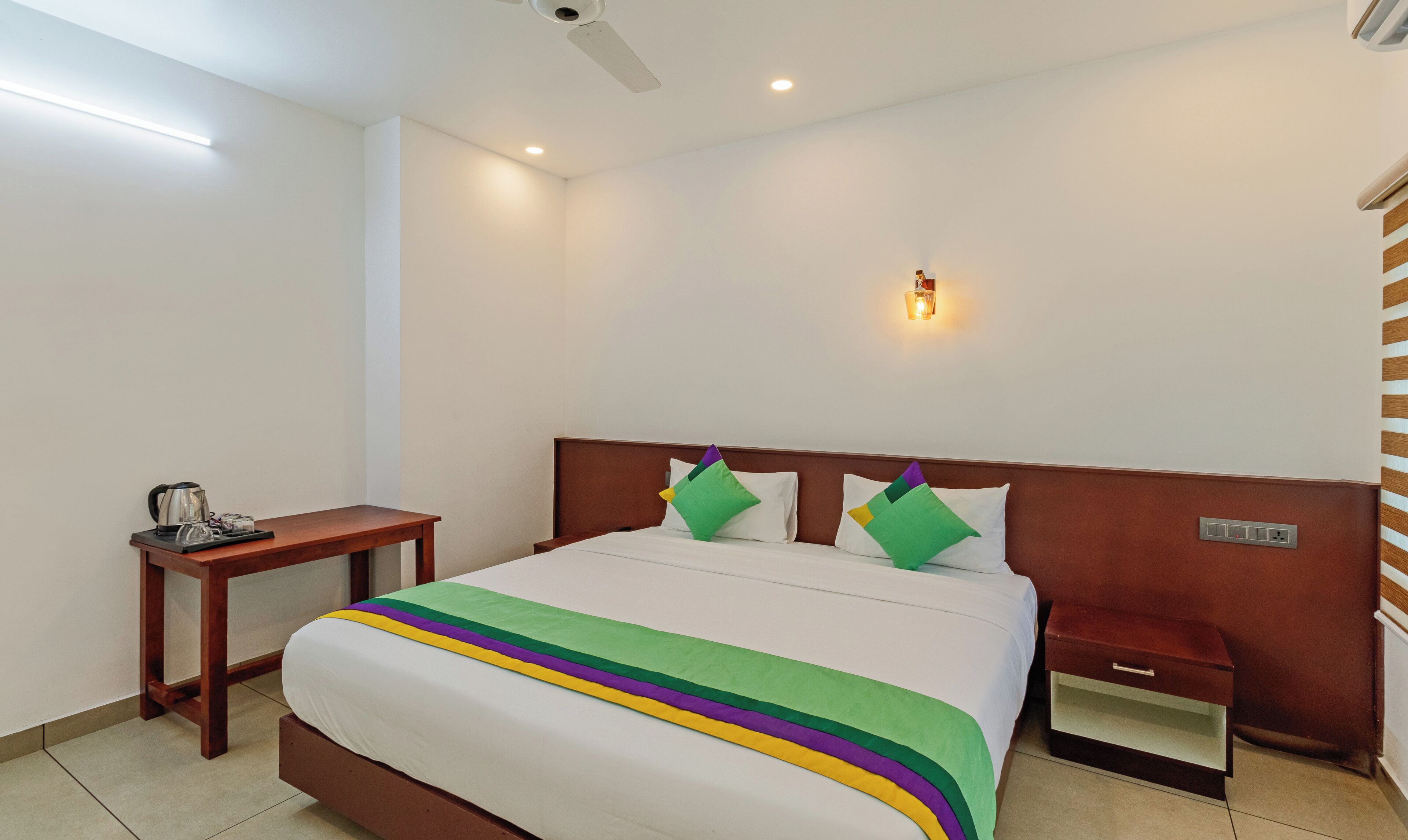 A hotel room with a bed, bedside table, and a nightstand.