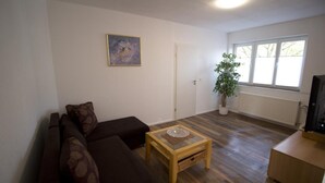 Ein Wohnzimmer mit einer Couch, einem Couchtisch, einer Topfpflanze und einem Fenster mit Blick.