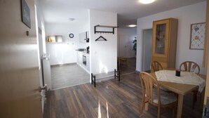 Eine moderne Küche mit weißen Schränken, einem Holzespeisesaal mit Stühlen und einer hängenden Garderobe.