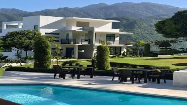 Un edificio moderno de dos pisos con piscina y zona de estar al aire libre.
