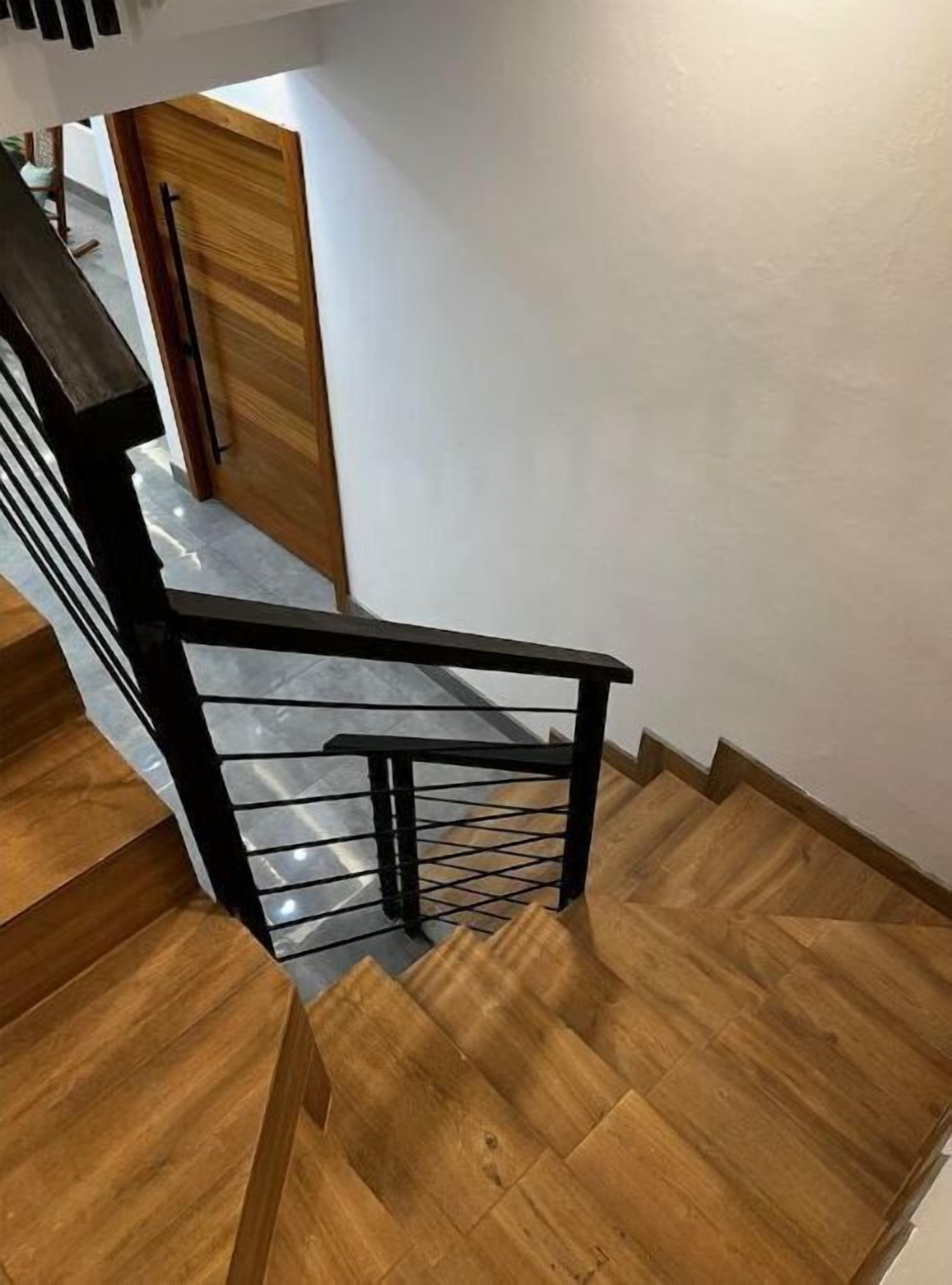Una escalera de madera con barandilla de metal negro.